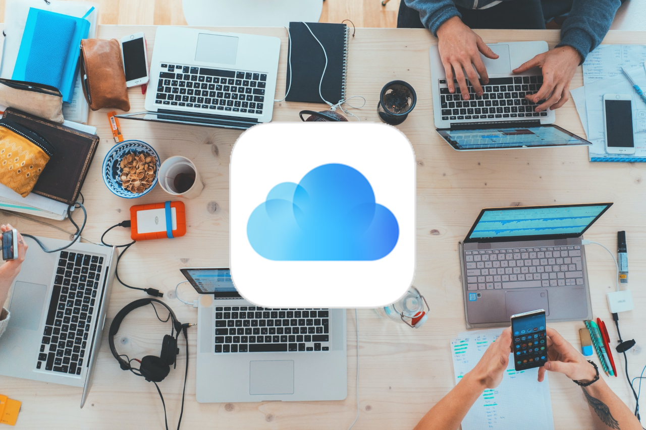 a Picture of several computers on a table with the iCloud logo.
